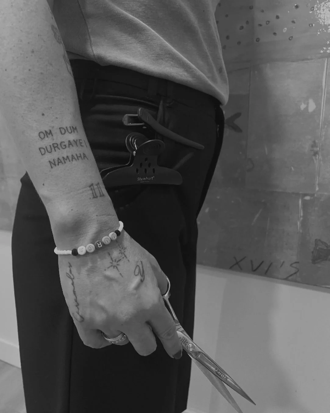Brazo de Tania con el mantra tatuado sujetando unas tijeras